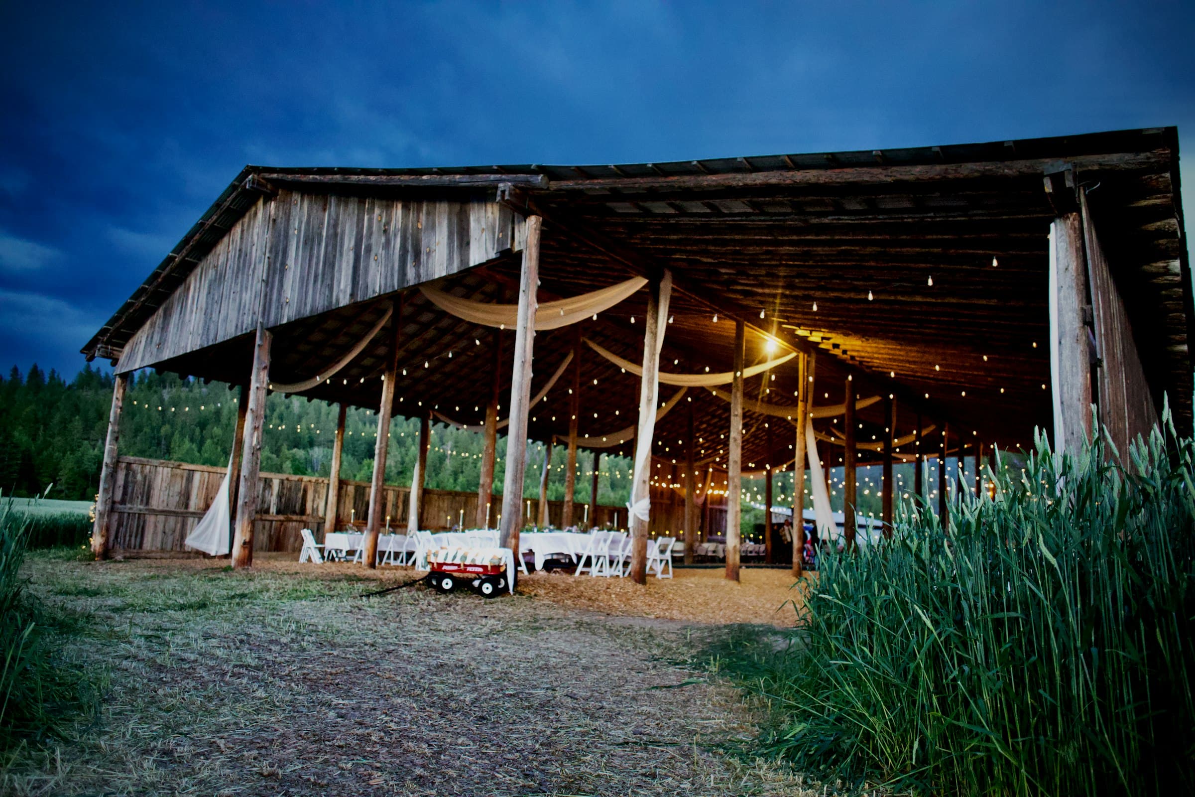 A barn wedding venue glowing with string lights at twilight