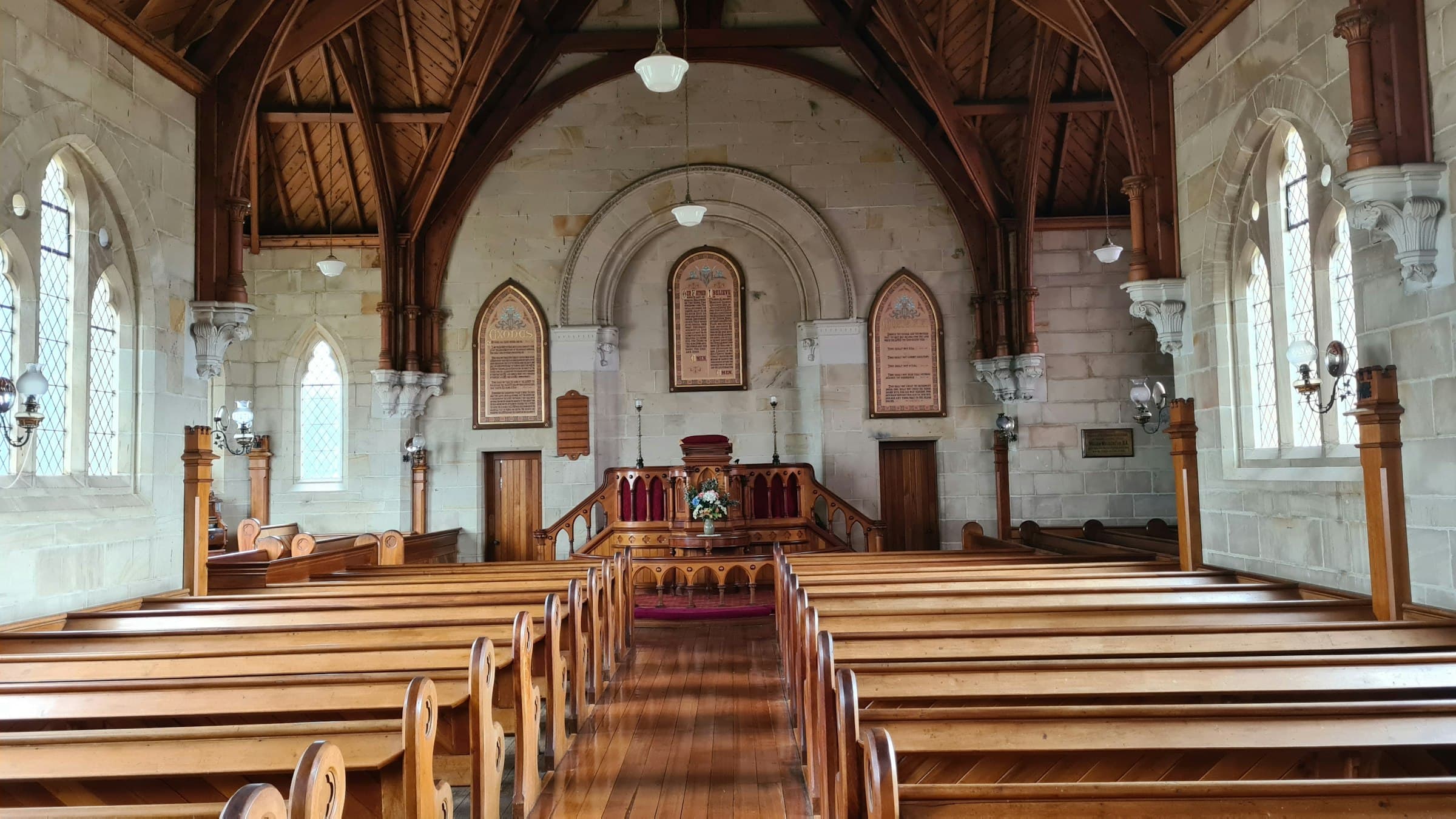 Sunlit stone chapel interior with wooden pews