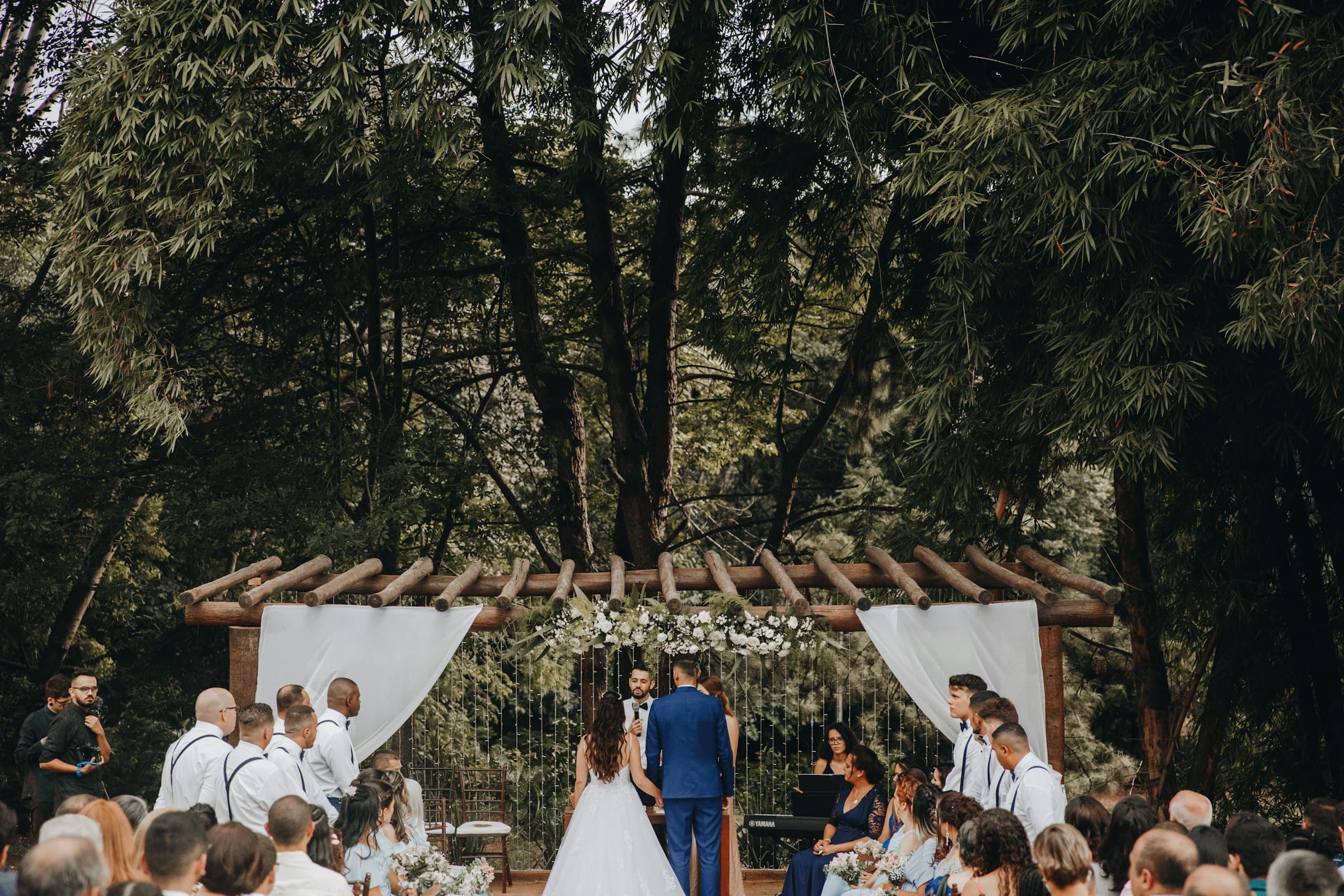An outdoor wedding ceremony in a sunlit forest clearing