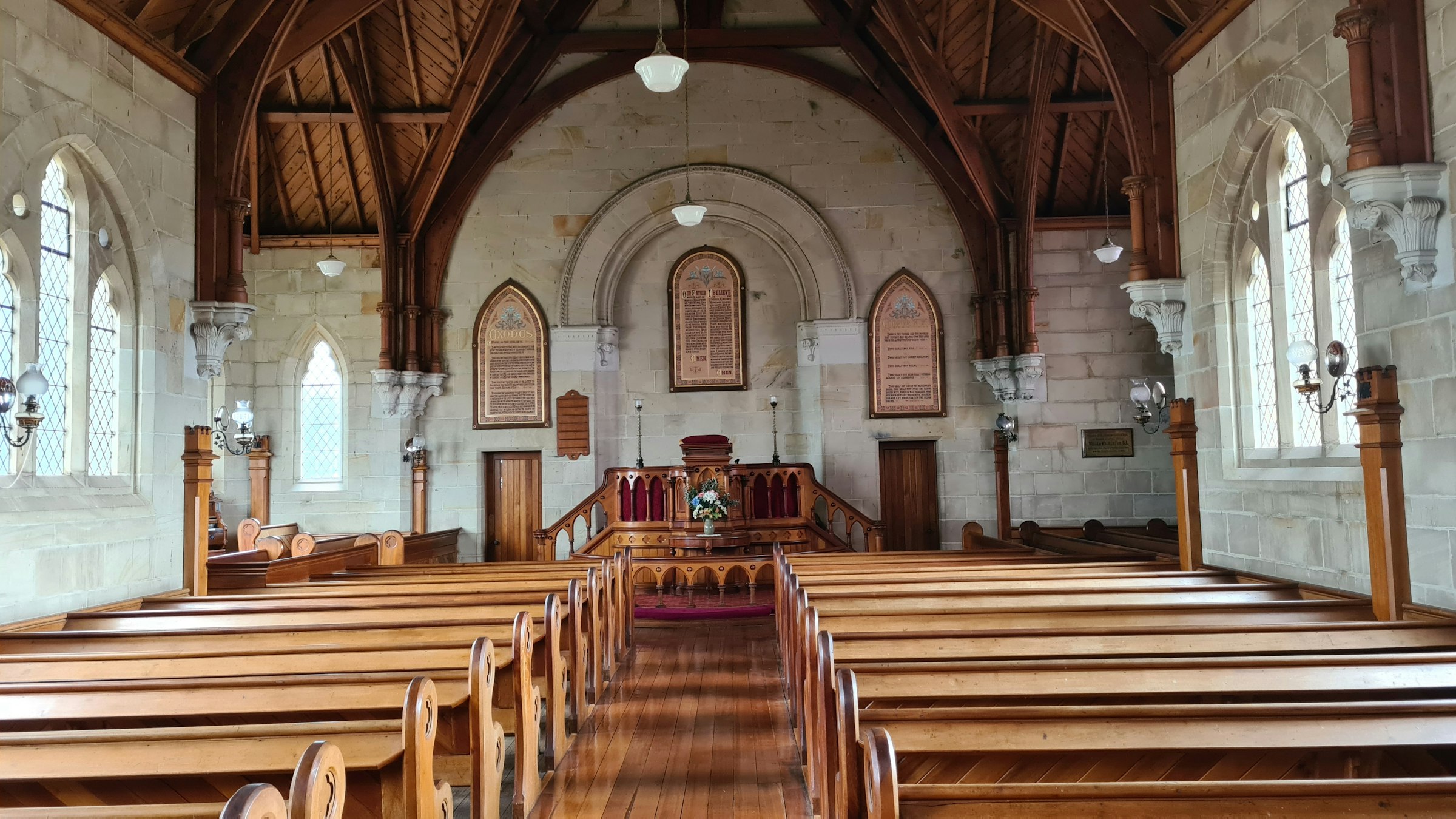 Sunlit stone chapel interior with wooden pews