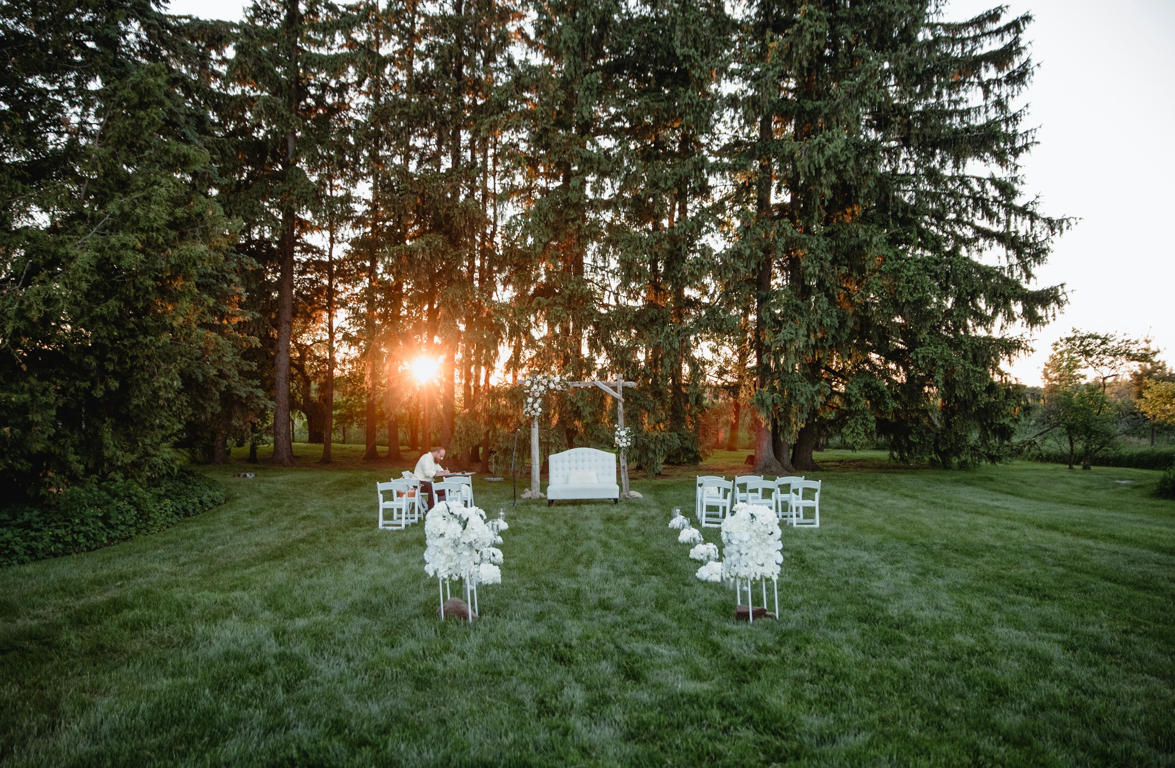 An outdoor wedding ceremony among tall pines at golden hour