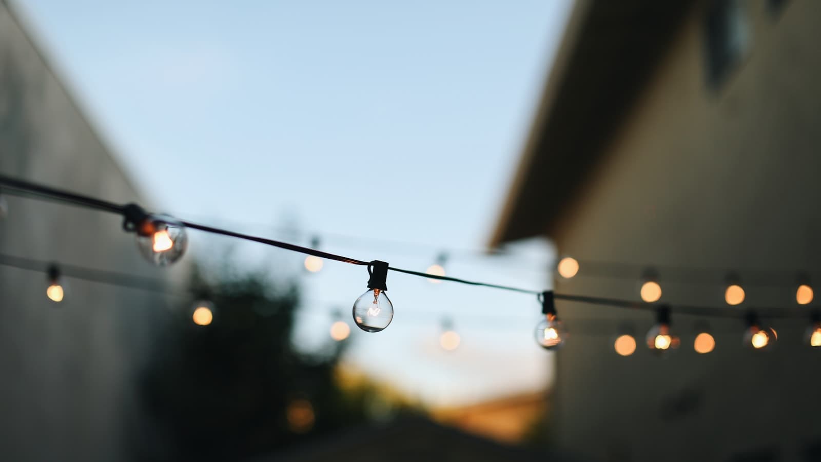 Beautifully decorated backyard wedding with string lights and long farm tables